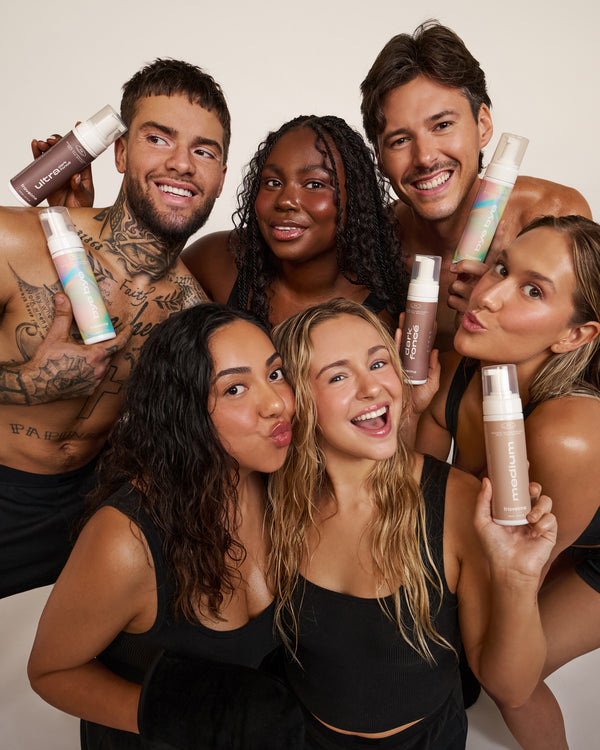Groupe de femmes et hommes, tout en sous-vêtements noirs, qui posent avec les nouveaux produits autobronzants de Travel Me. Marque self-care québécoise.