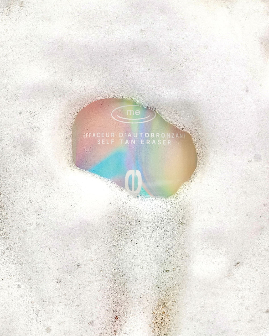 Produit Effaceur d'autobronzant à l'emballage multicolore et métallique, avec de la mousse blanche tout autour, de l'entreprise québécoise TravelMe.