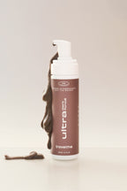 Mousse autobronzante Ultra Foncé, avec de la mousse qui coule, de l'entreprise québécoise TravelMe, sur un fond blanc.